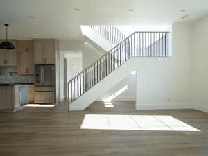 Staircase featuring wood finished floors, a towering ceiling, and recessed lighting