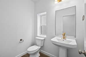 Half bathroom with toilet and wood finished floors