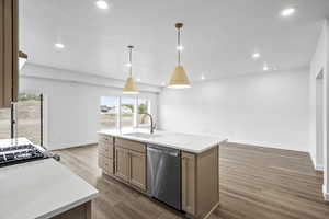 Kitchen with a textured ceiling, stainless steel dishwasher, wood finished floors, light countertops, and a kitchen island with sink