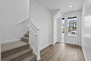 Foyer entrance featuring wood finished floors, stairs, and recessed lighting