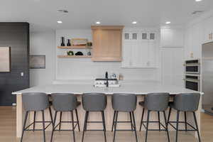 Kitchen featuring light wood finished floors, recessed lighting, white cabinetry, appliances with stainless steel finishes, and decorative backsplash
