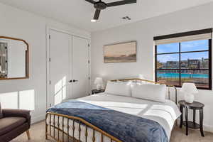 Bedroom featuring light colored carpet, a closet, and a ceiling fan