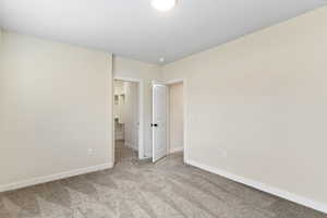 Unfurnished bedroom featuring light carpet and a walk in closet