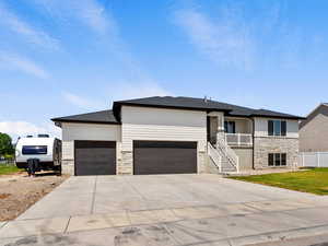 Prairie-style house featuring stone siding, an attached garage, concrete driveway, and stairway