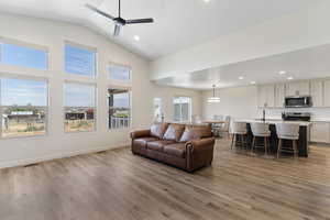 Living area with recessed lighting, light wood-style floors, ceiling fan, and high vaulted ceiling