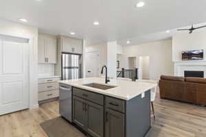 Kitchen featuring gray cabinetry, a fireplace, stainless steel appliances, open floor plan, and recessed lighting