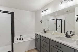 Full bathroom featuring a stall shower, a garden tub, double vanity, and wood finished floors