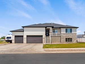 Prairie-style house featuring stone siding, a garage, driveway, and a shingled roof