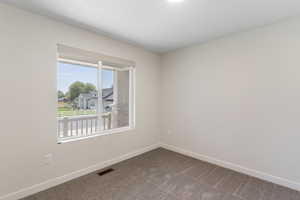 Spare room with dark colored carpet and baseboards