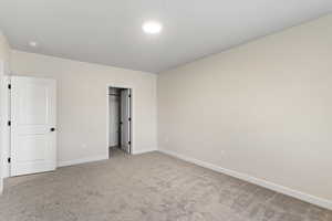 Unfurnished bedroom with carpet and a walk in closet