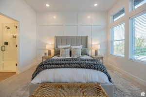 Carpeted bedroom featuring a decorative wall, multiple windows, and recessed lighting