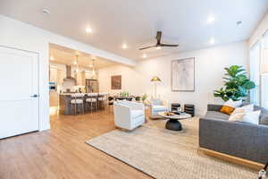Living area with a ceiling fan, light wood-style flooring, and recessed lighting