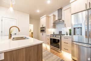 Kitchen featuring stainless steel appliances, wall chimney range hood, light countertops, modern cabinets, and recessed lighting