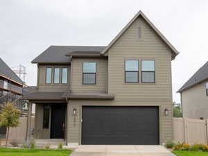 View of front of property with concrete driveway, a garage, and a gate