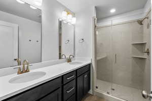 Full bathroom with a textured ceiling, double vanity, a stall shower, recessed lighting, and wood finished floors