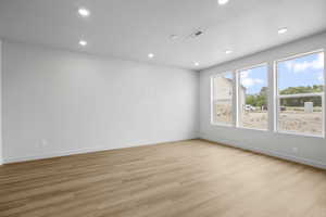 Spare room with light wood-type flooring, a textured ceiling, and recessed lighting