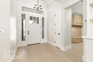 Foyer with light wood-style floors and a chandelier