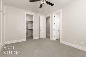 Unfurnished bedroom with carpet, a spacious closet, and a ceiling fan