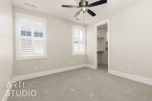 Unfurnished bedroom featuring carpet flooring, a spacious closet, and ceiling fan