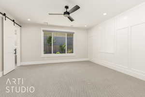 Unfurnished room featuring a barn door, light colored carpet, crown molding, recessed lighting, and a decorative wall
