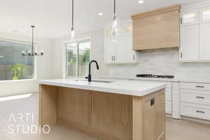 Kitchen featuring light wood-type flooring, a kitchen island with sink, light countertops, glass insert cabinets, and recessed lighting