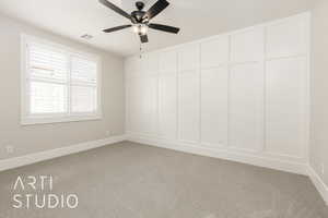 Spare room featuring light carpet, a ceiling fan, and a decorative wall