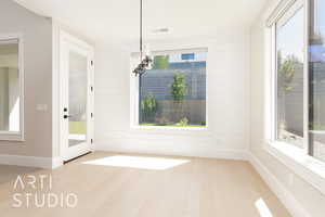 Unfurnished dining area with healthy amount of natural light, light wood-style floors, and wood walls