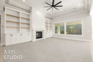 Unfurnished living room featuring built in shelves, light carpet, a glass covered fireplace, recessed lighting, and crown molding