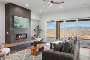 Living room with wood finished floors, a fireplace, recessed lighting, and a ceiling fan