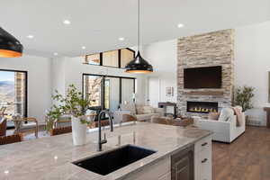 Kitchen featuring light stone counters, wine cooler, a fireplace, pendant lighting, and recessed lighting