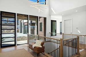 Living area featuring hardwood / wood-style flooring, recessed lighting, a high ceiling, and an upstairs landing