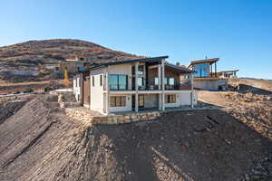 Rear view of house with a balcony, a mountain view, and a patio area