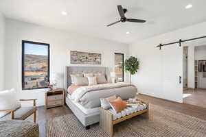 Bedroom featuring a barn door, wood finished floors, recessed lighting, a ceiling fan, and multiple windows