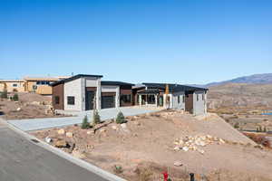 View of front of house featuring stone siding, driveway, a patio area, and a mountain view