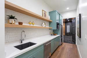 Kitchen with open shelves, tasteful backsplash, dark wood-type flooring, green cabinetry, and appliances with stainless steel finishes