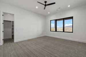 Unfurnished bedroom featuring a spacious closet, recessed lighting, carpet floors, ceiling fan, and a mountain view