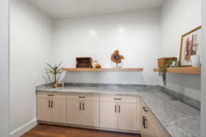 Kitchen featuring dark wood-style flooring, cream cabinets, and open shelves