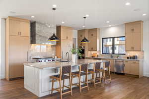 Kitchen with tasteful backsplash, light brown cabinetry, light stone countertops, decorative light fixtures, and recessed lighting