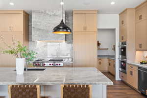 Kitchen featuring light brown cabinets, recessed lighting, light stone counters, dark wood-style floors, and appliances with stainless steel finishes