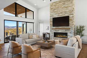 Living room featuring hardwood / wood-style flooring, a towering ceiling, a fireplace, and recessed lighting