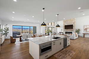 Kitchen with open floor plan, light stone countertops, hanging light fixtures, a fireplace, and white cabinets