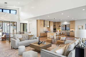 Living area featuring light wood-style flooring, recessed lighting, and a towering ceiling