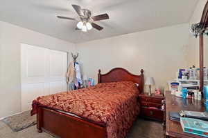 Bedroom with a textured ceiling, carpet floors, and ceiling fan
