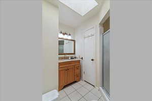 Bathroom featuring a skylight, vanity, tile patterned flooring, and a shower stall
