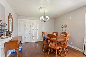 Dining area featuring a textured ceiling, wood finished floors, and a chandelier
