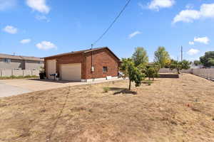 View of property exterior featuring a garage, concrete driveway, and brick siding