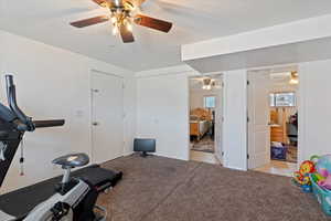 Workout area with light carpet, a textured ceiling, and light tile patterned floors
