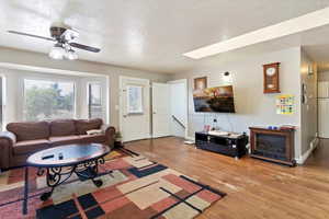 Living area featuring a textured ceiling, light wood-style flooring, and ceiling fan