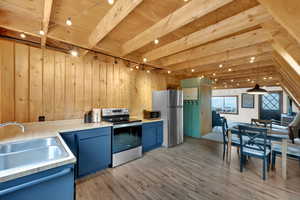 Kitchen featuring wood walls, blue cabinets, stainless steel appliances, light countertops, and light wood-style floors