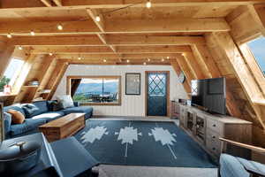 Living room featuring carpet, wooden walls, and a wood ceiling with exposed beams